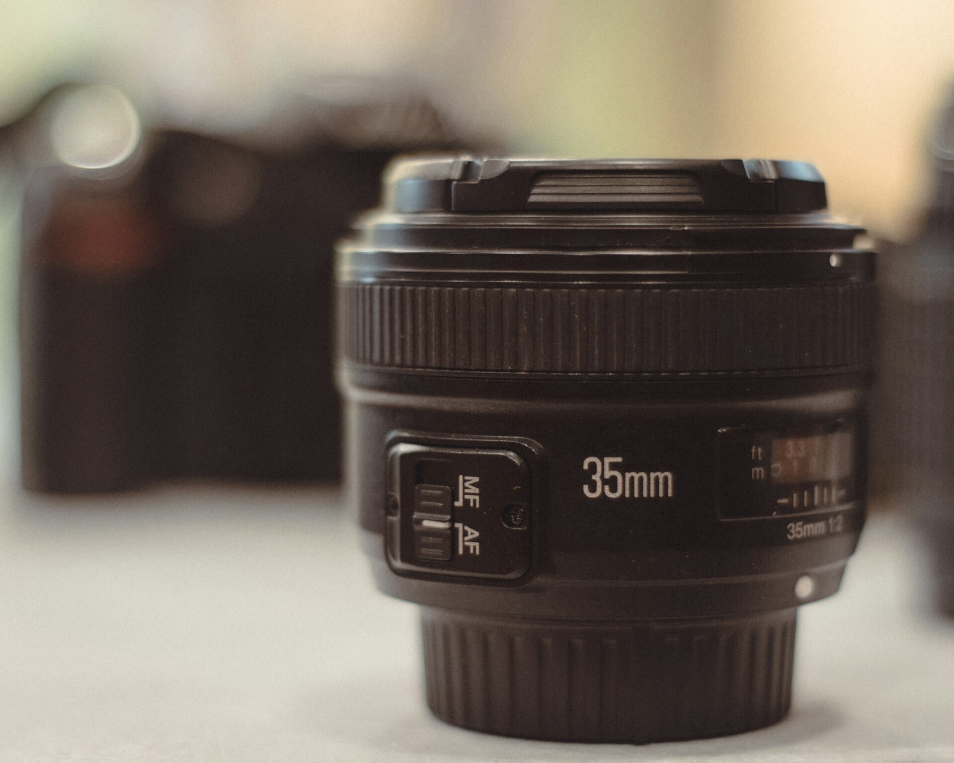 Yongnuo 35mm f/2 objektív élességállító kapcsolójának részlete. Közelkép egy fekete Yongnuo 35mm f/2 autofókuszos objektívról, az oldalán lévő AF/MF kapcsolóval.